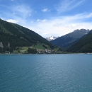 Ihned za průsmykem Reschenpass se modrá hladina rozlehlé přehradní nádrže Reschensee (Lago di Resia)